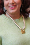 Woman wearing a chunky, neutral, statement necklace for women featuring Amethyst, wood beads, and a square gold pendant handmade by women in Charlotte, NC, USA.