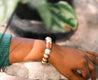 Woman wearing a neutral, beaded, lightweight bracelet handmade by artisans in Charlotte, NC, USA.