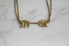 A unique necklace with arrow-like details handcrafted out of recycled artillery shells collected from past violence by artisans in Ethiopia.
