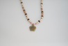 Mostly neutral with pops of pink long, beaded necklace featuring a green stone flower pendant, handmade by artisans overcoming trauma and injustice in Charlotte, NC.