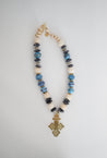 Chunky statement necklace in beautiful blue tones made with sustainable recycled paper beads, featuring a unique brass Ethiopian coptic cross pendant. 
