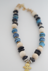 Chunky statement necklace in beautiful blue tones made with sustainable recycled paper beads, featuring a unique brass Ethiopian coptic cross pendant. 