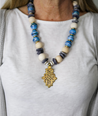 Chunky statement necklace in beautiful blue tones made with sustainable recycled paper beads, featuring a unique brass Ethiopian coptic cross pendant.
