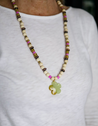 Mostly neutral with pops of pink long, beaded necklace featuring a green stone flower pendant, handmade by artisans overcoming trauma and injustice in Charlotte, NC.