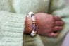 Woman wearing a beaded bracelet featuring recycled glass beads and neutral colors, handmade by artisans in Charlotte, NC, USA.