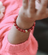 Woman wearing a hot pink and cranberry lightweight beaded bracelet handmade by artisans in Charlotte, NC, USA overcoming trauma and injustice.