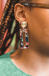 Woman wearing acrylic, lightweight, and multicolor rectangle earrings with a gold topper handmade by artisans in Charlotte, NC, USA.