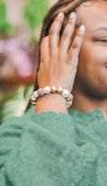 Woman wearing a neutral, beaded, lightweight bracelet handmade by artisans in Charlotte, NC, USA.