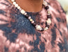 Woman wearing a lightweight statement necklace featuring wood and recycled glass purple beads handmade by artisans in Charlotte, NC, USA.