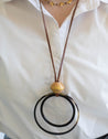 Woman wearing handmade long leather cord necklace with double circle pendant at bottom