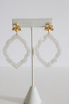 Pair of gold flowers and white resin earrings.