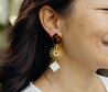 Handmade dangle earrings with a tortoise shell topper, gold-plated sun middle charm, and diamond-shaped cattle horn charm at the end