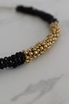 close up shot of a black and gold beaded collar necklace on brass cord