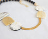 Unique, asymmetrical statement necklace featuring cattle horn pendants, gold-plated metal, and lightweight wood beads