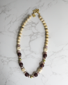 A lightweight statement necklace featuring wood and recycled glass purple beads handmade by artisans in Charlotte, NC, USA.
