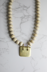 A chunky, neutral, statement necklace for women featuring Amethyst, wood beads, and a square gold pendant handmade by women in Charlotte, NC, USA.