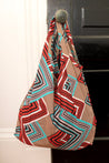Geometric patterned tote bag with bold red, teal, black, and beige zigzag and striped design.