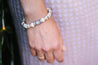 beaded bracelet in cream, gold accents with a sunbeam pendant in black and white