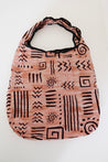 Pink patterned bag with black designs.