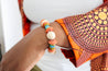 orange, blue, green bracelet made out of wood, glass, and clay.